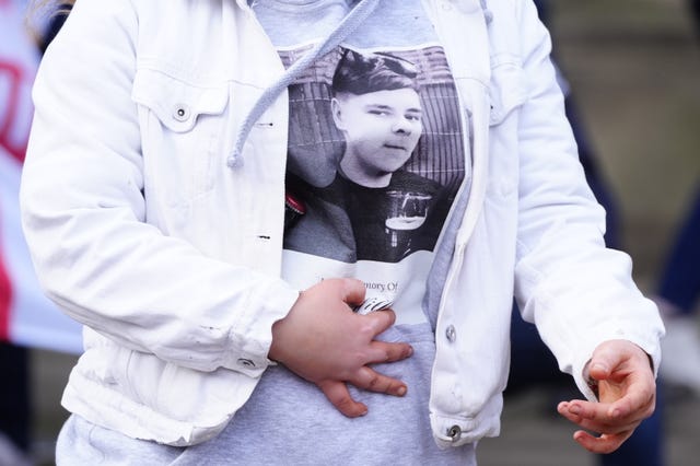 A mourner wearing a top displaying an image of Harvey Willgoose