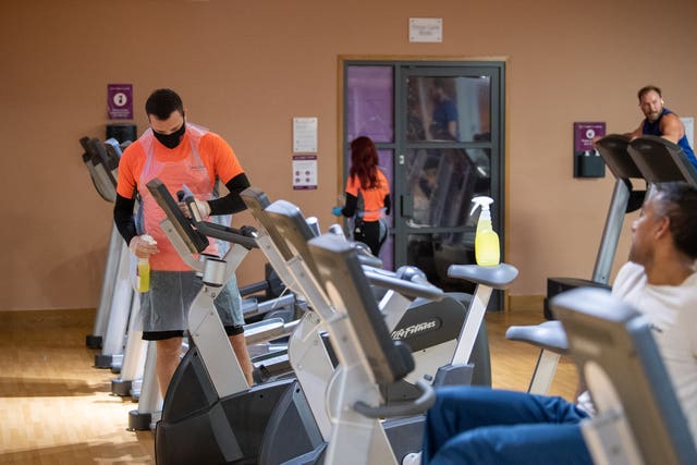 Members of staff clean gym equipment at David Lloyd health club in Leicester as they reopen after England's second national lockdown ended (Joe Giddens/PA)