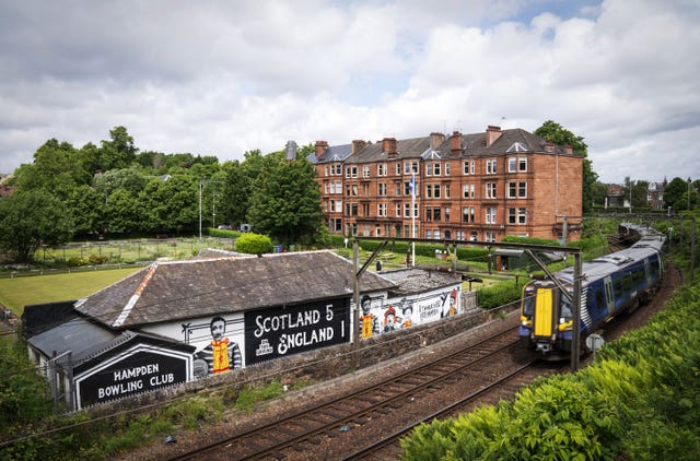 A train passing by a mural which says Scotland 5 England 1