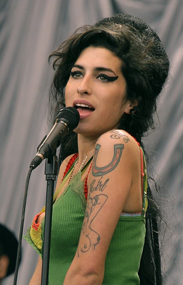 Amy Winehouse performing on stage, wearing a green vest top