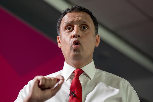 Head and shoulders photo of Anas Sarwar delivering a speech, with one hand raised in front of his chest