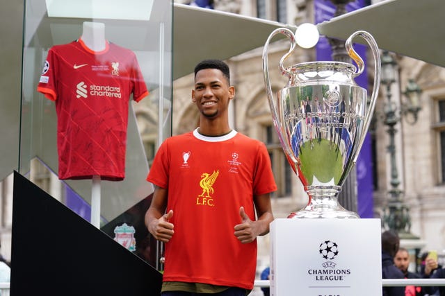 A Liverpool fan poses next to the Uefa Champions League trophy (Adam Davy/PA)