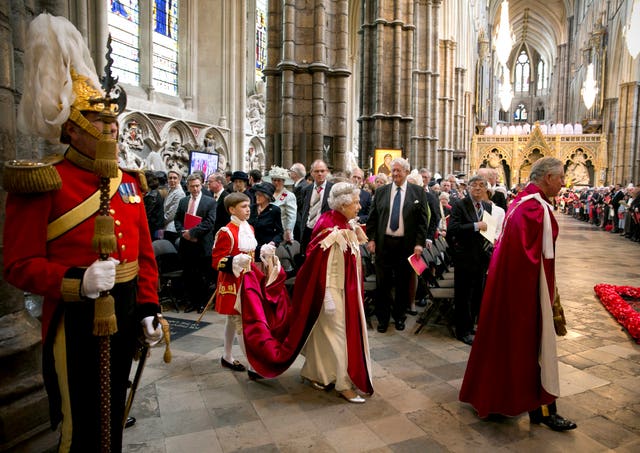 Queen Elizabeth II, with a Page of Honour carrying her robes, and the then-Prince of Wales during procession in 2014 