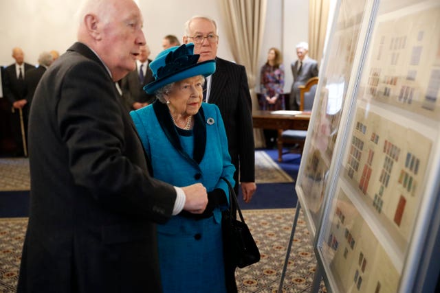 The Queen is shown stamps of previous British monarchs during a visit to the new headquarters of the Royal Philatelic Society
