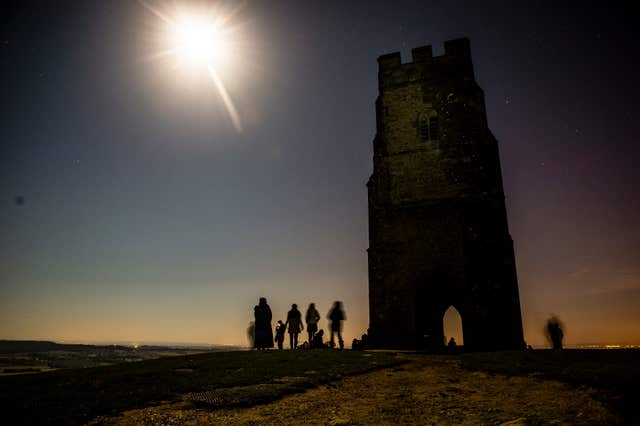 People watch a blood red supermoon in the skies above Glastonbury Tor 