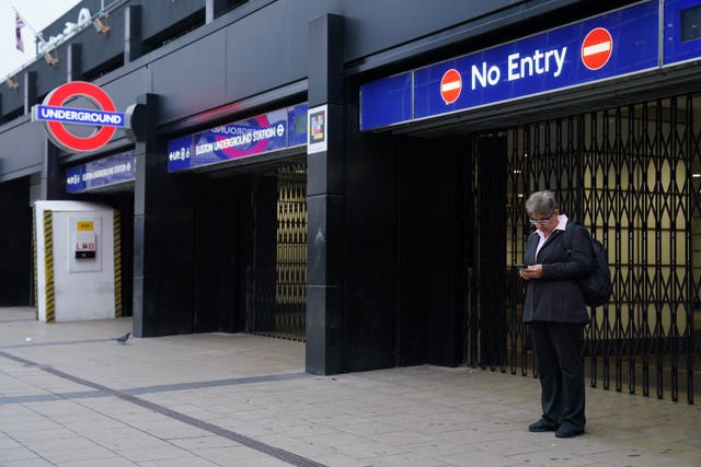 A commuter stands by the closed shutters at the entrance to Euston Underground station in central London during a strike by members of the Rail, Maritime and Transport union (RMT) and Unite in a long-running dispute over jobs and pensions