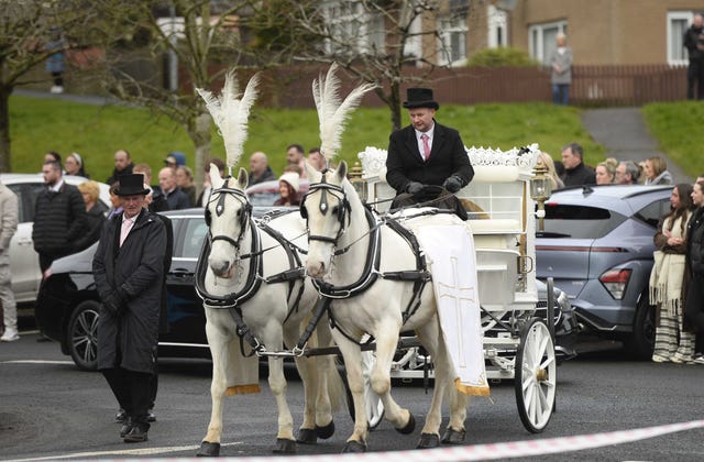 A horse-drawn hearse leads the funeral cortege 