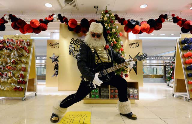 An actor dressed as Santa holds a guitar at the launch of the Selfridges Christmas shop at the flagship store on Oxford Street