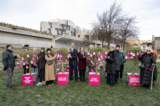 Liam McArthur with assisted dying supporters and signs reading ' let us choose' and 'legalise assisted dying'