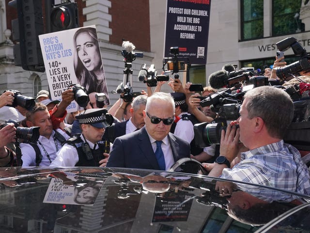 Huw Edwards surrounded by journalists and photographers when leaving court