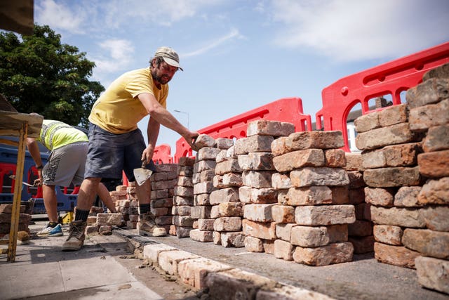 Two men build a brick wall