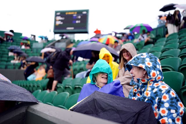 Spectators shelter from the rain on day seven of the 2024 Wimbledon in London