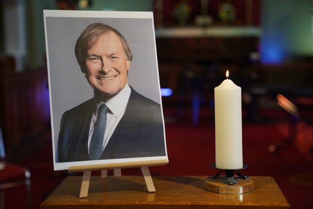 A candle and a photo at a vigil at St Michael & All Angels church in Leigh-on-Sea Essex for Conservative MP Sir David Amess