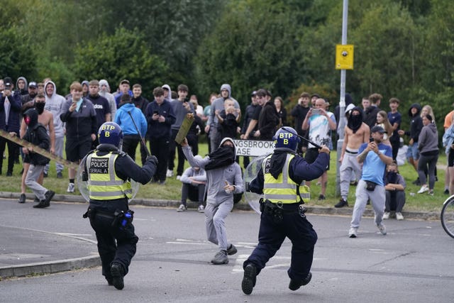 A man throws a piece of wood at police