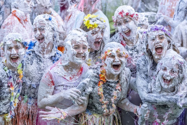 Students in floral headdresses and grass skirts covered in shaving foam