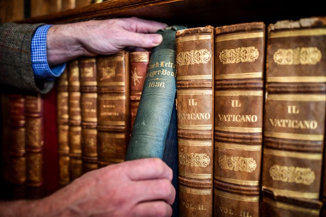 Man putting book on bookshelf.