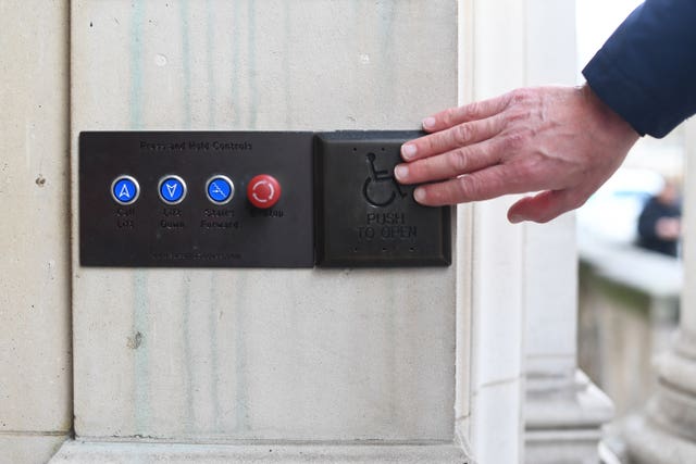 A picture posed by a model of a man using a disabled access button (Victoria Jones/PA)