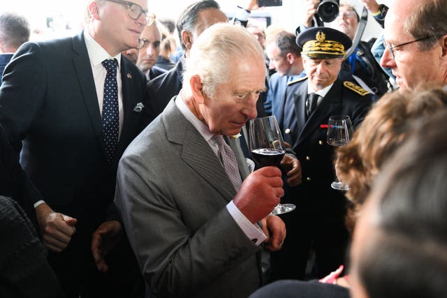 Charles smelling a glass of red wine on day three of the state visit to France