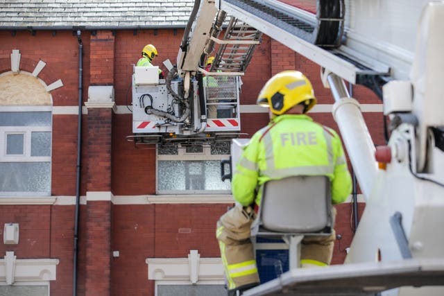 A firefighter in a cherry picker repairs a window