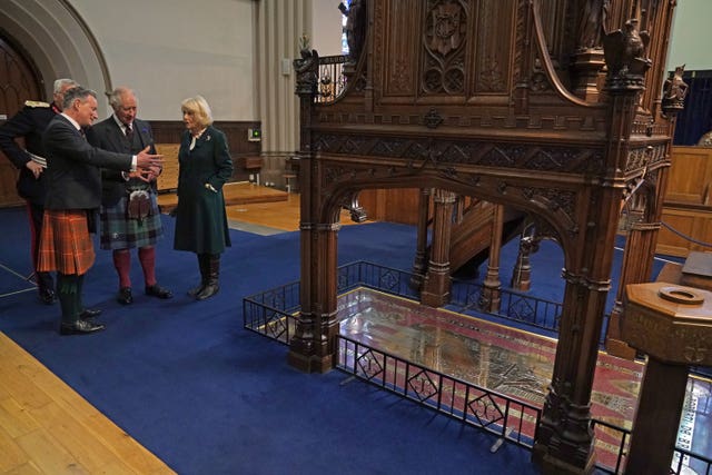 King Charles III and the Queen Consort are shown the grave stone of Robert the Bruce during a visit to Dunfermline Abbey, to mark its 950th anniversary, after attending a meeting at the City Chambers in Dunfermline, Fife, where the King formally marked the conferral of city status on the former town