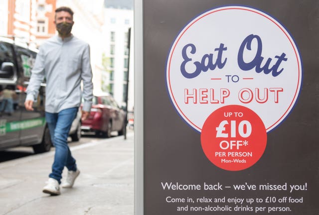 A man passing a sign advertising the ‘Eat Out to Help Out’ scheme