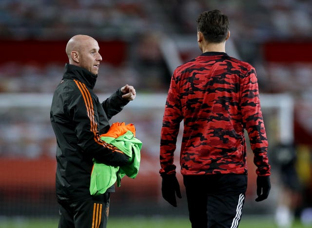 Manchester United first team development coach Nicky Butt (left) oversees the players warming up on the pitch ahead