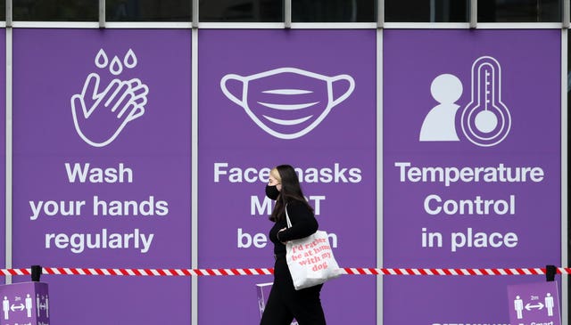 Women in mask walking below a sign