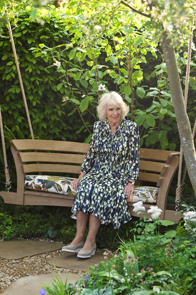 Camilla sits on a swing bench 