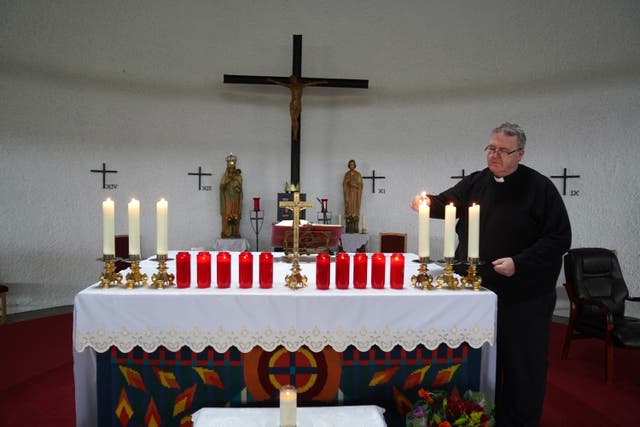 Father John Joe Duffy lights 10 red candles candles at St Michael’s Church in Creeslough Co Donegal, for the victims of the Applegreen service station explosion