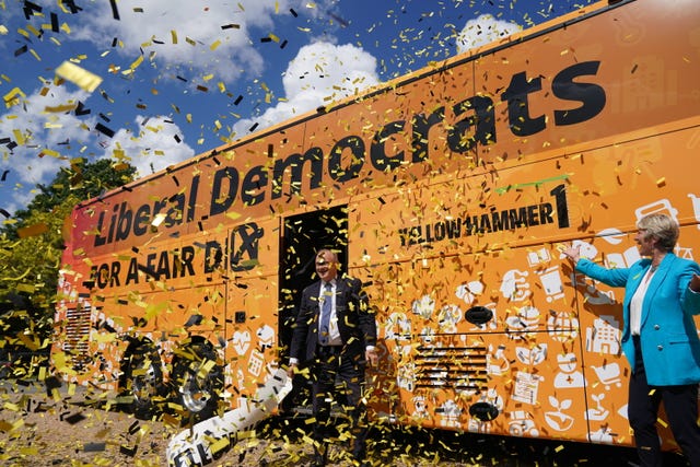 Liberal Democrat leader Sir Ed Davey stands outside his party's election bus showered in confetti
