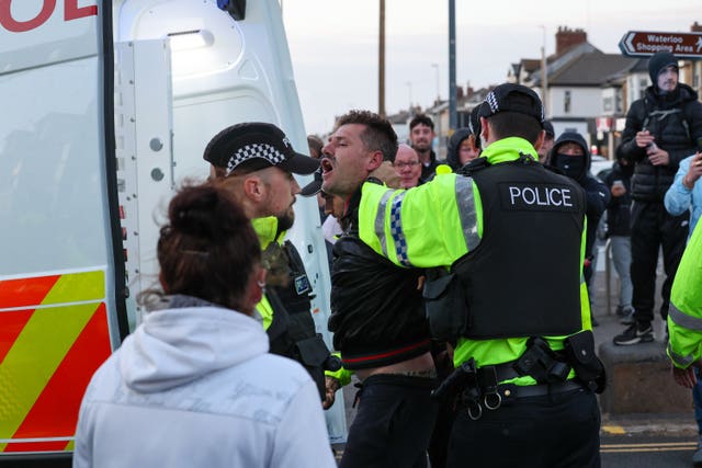 Police officers force a man into the back of a police van during disorder in Blackpool.