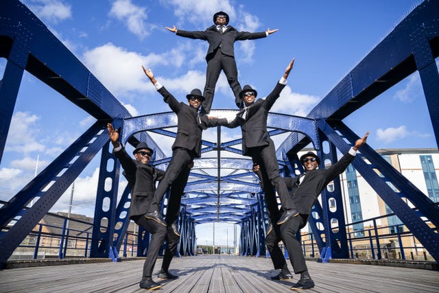 Performers stand on each other on a bridge