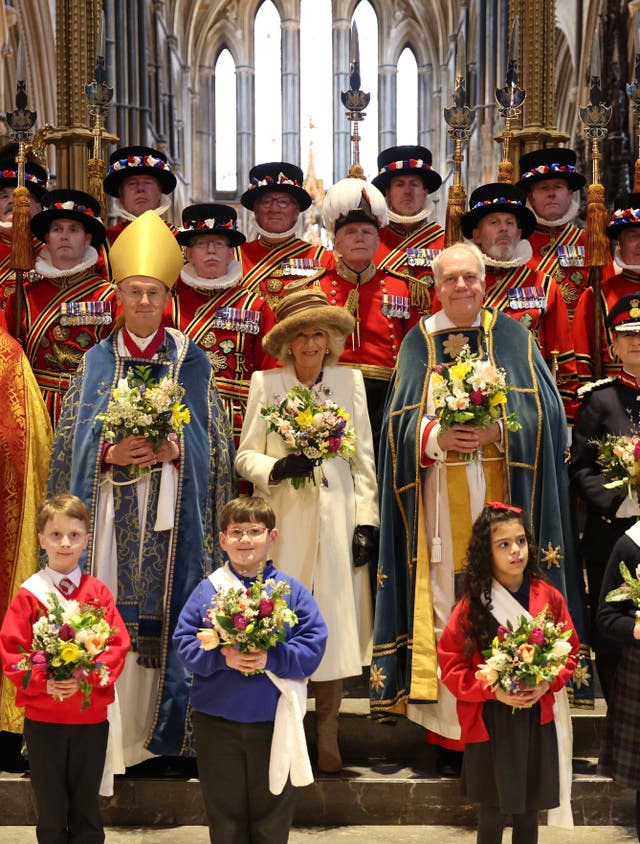 Queen Camilla holds the Nosegay bouquet as she poses with Yeomen of the Guard and religious representatives as she attends the Royal Maundy service at Worcester Cathedral