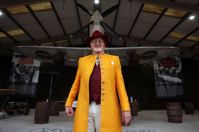 A man wearing a mustard yellow jacket stands in front of an airplane display