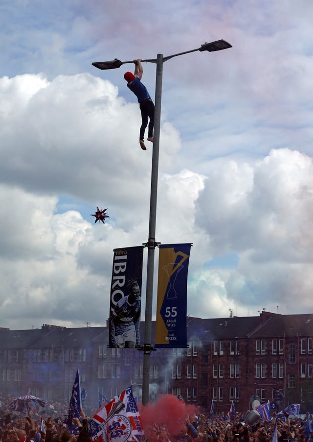 A Rangers fan clings on to a lamp post outside Ibrox 
