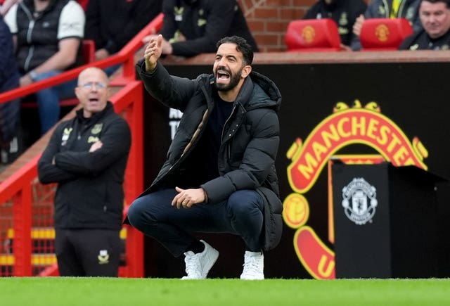 Ruben Amorim raises his right hand as he crouches down in his technical area