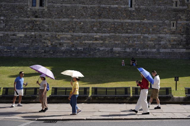 People use umbrellas to shade themselves from the sun in Windsor, Berkshire