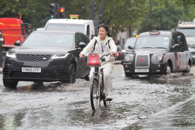 A cyclist rides through a puddle on Euston Road in London