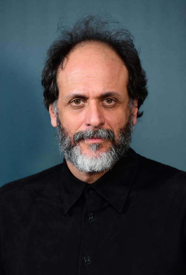 Luca Guadagnino wearing a black suit staring at the camera.