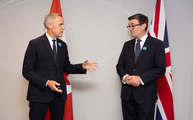 Mark Carney, left, and Andy Burnham standing in front of Canadian and UK flags