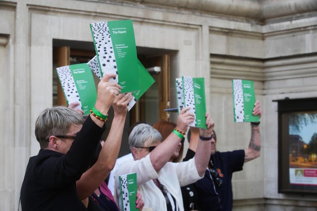 People hold up copies of the Infected Blood Inquiry report