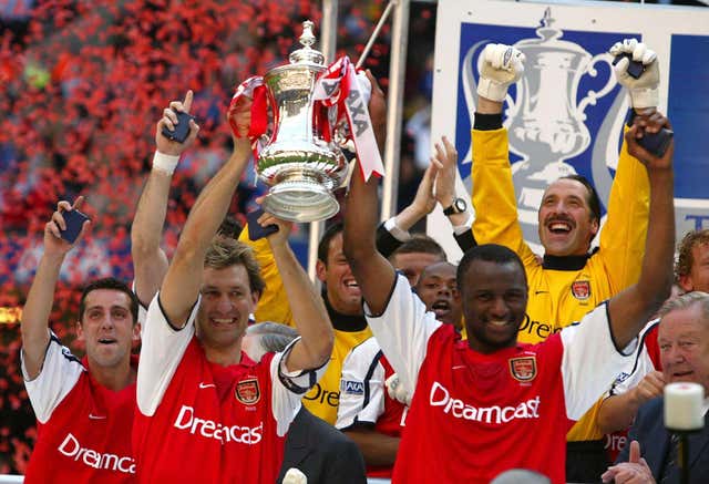 Arsenal captain Tony Adams and Patrick Vieira lift the FA Cup as team-mate Edu (far left) looks on