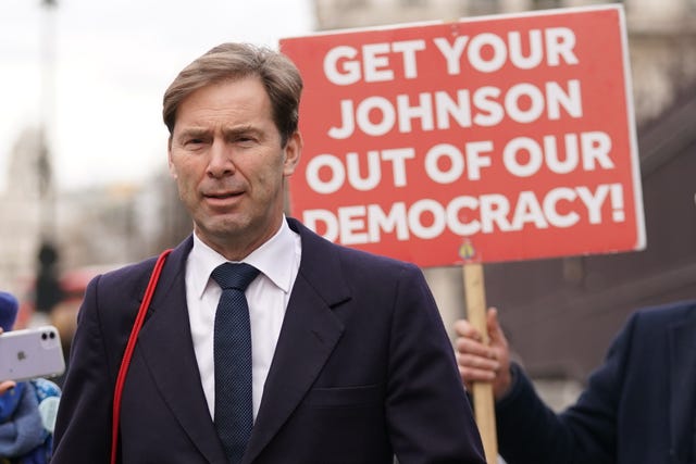 Former minister Tobias Ellwood is followed by protesters