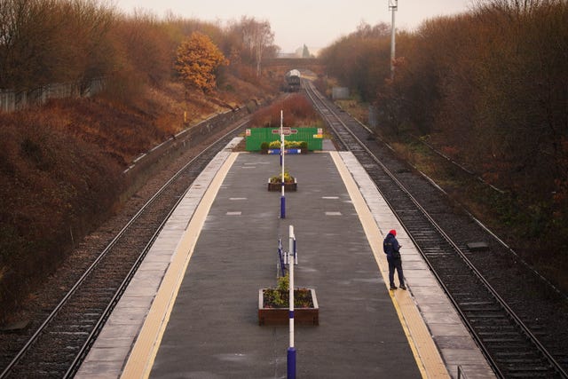 A passenger waits for a train at Denton railway station in Greater Manchester 