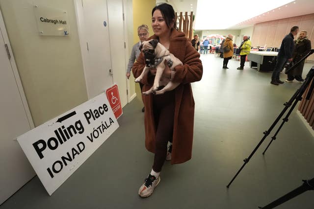 A woman walks down a corridor with her pet pug under her arm