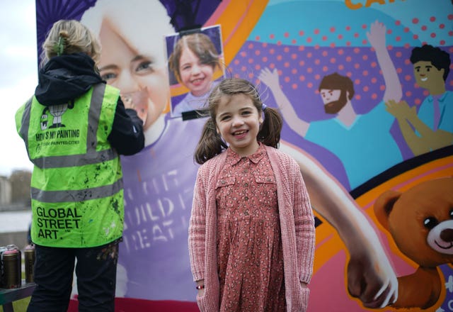 Six-year-old Sienna Halls, from Ruislip in London, next to an 8ft mural at Potters Fields Park in London