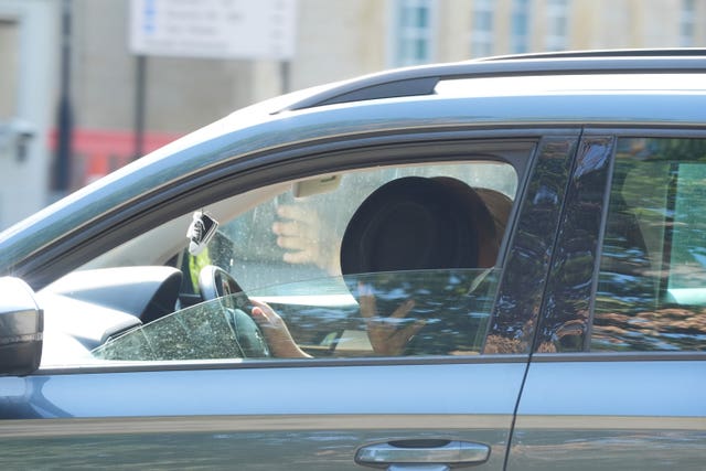 Suspended Labour councillor Ricky Jones, hiding behind his hat in a car as he leaves Snaresbrook Crown Court