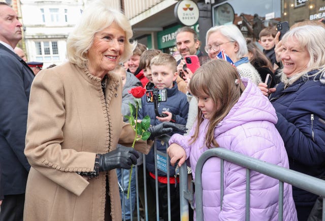 Camilla smiles after receiving a red rose from a girl 