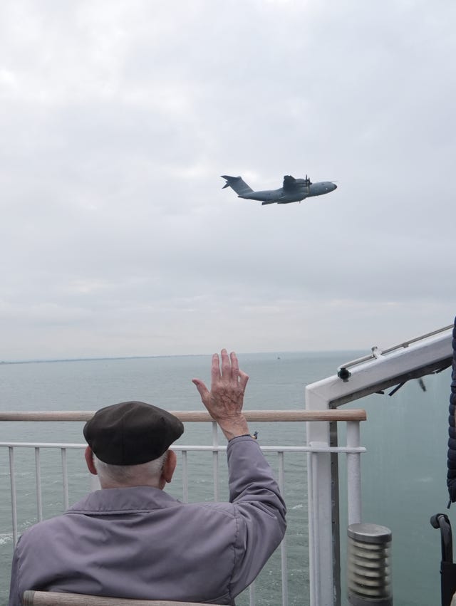 A veteran waves to a Royal Air Force flypast over the Brittany Ferries ship Mont St Michel as it sails out of Portsmouth Harbour (Jordan Pettit/PA)
