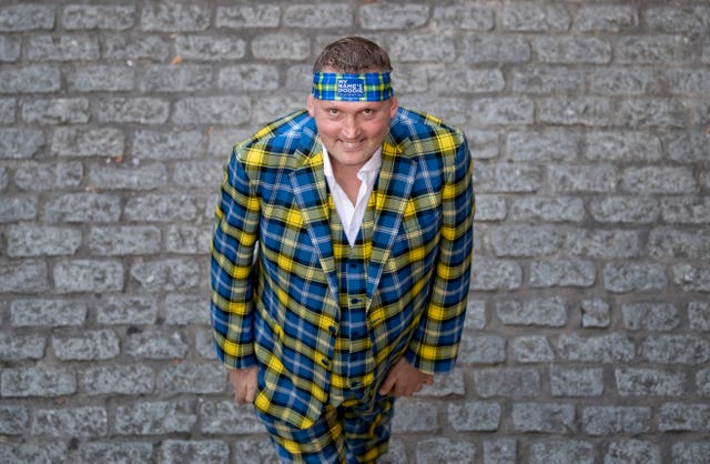 Doddie Weir smiling, while wearing a yellow and blue tartan suit and matching bandana